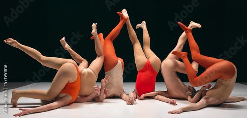 Legs up. Group of young girls, experimantal dancers performing on stage in bodysuits. Creative and artistic dancers. Concept of art, movement, youth, fashion, lifestyle, flexibility, inspiration photo