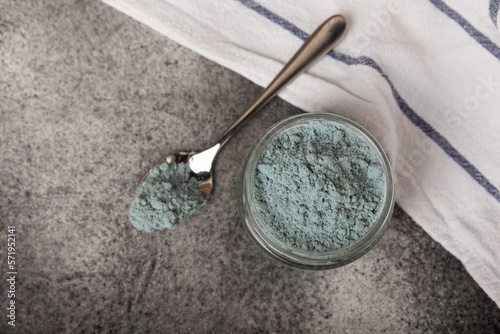 Blue spirulina powder in a glass jar on a black texture background. Natural superfood, vegan, healthy food supplement. Phycocyanin extract. Antioxidant. Place for text. Copy space.