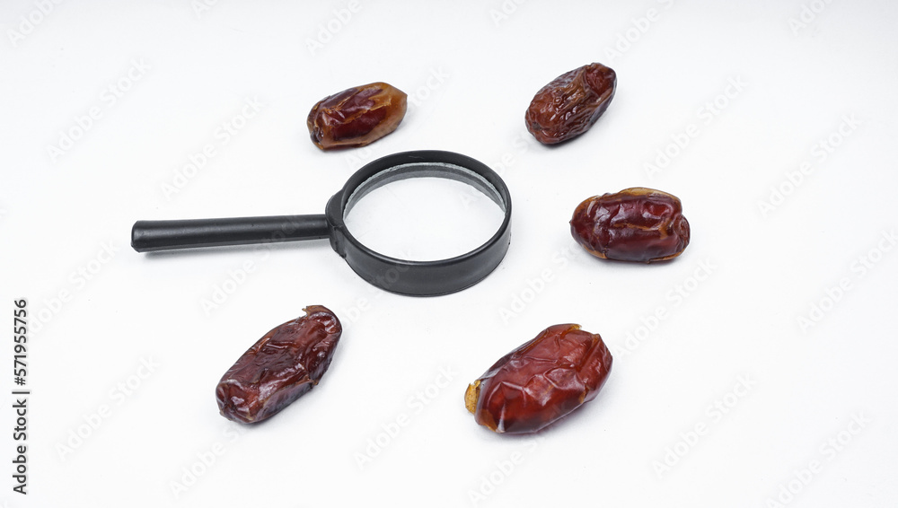 Kurma or dates fruits isolated with magnifiying glass on white background Kurma or dates fruits isolated with magnifiying glass on white background