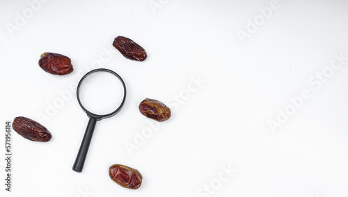 Kurma or dates fruits isolated with magnifiying glass on white background photo