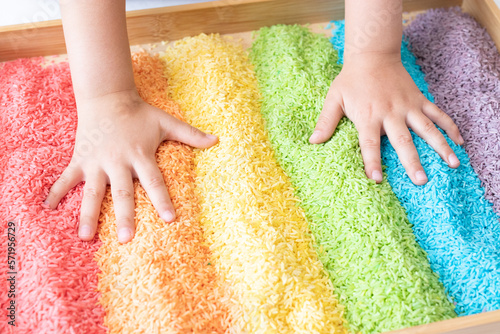 Hands in a rainbow sensory bin