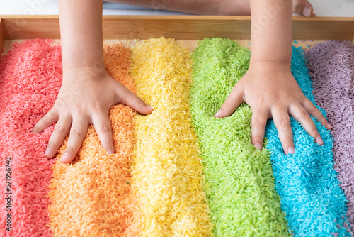 Hands in a rainbow sensory bin photo