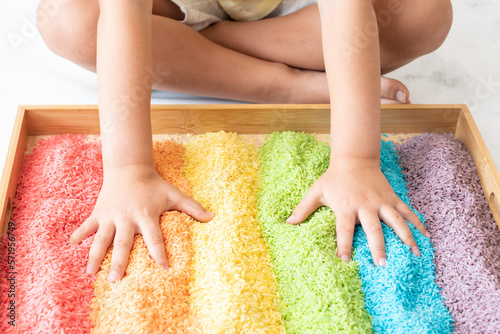 Hands in a rainbow sensory bin