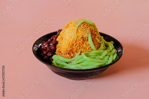 Low angle view of popular traditional local cold dessert cendol, shaved ice drizzled in gula melaka syrup with green noodles and red beans photo