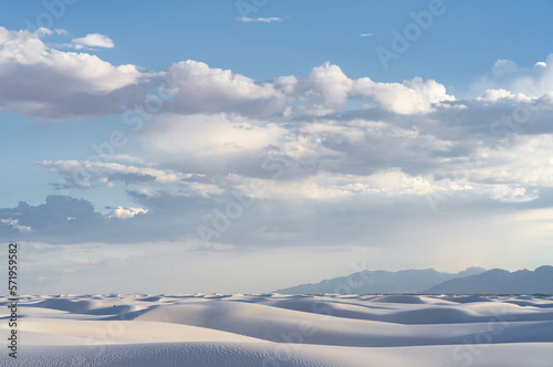 A landscape view of a sun setting over White Sands National Park on a cloudy evening