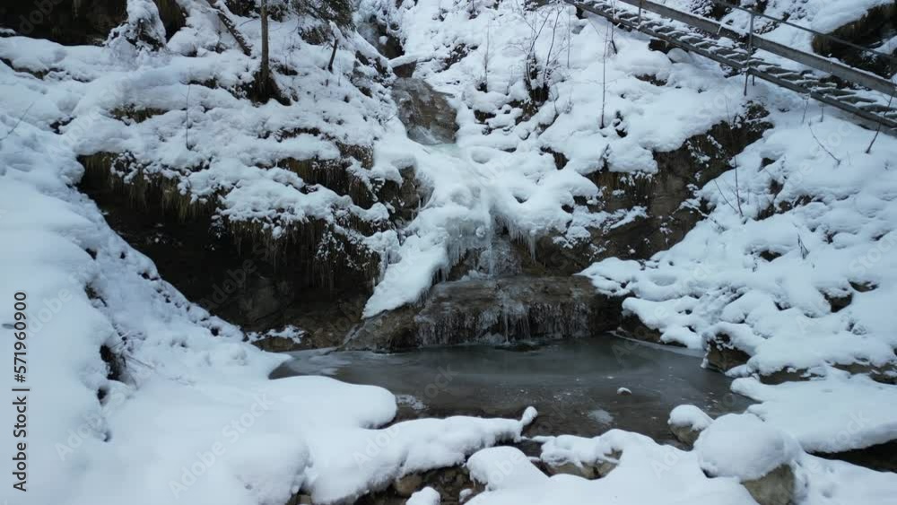 the alps in winter with trees and rocks standing on a mountain and covered with snow videographed with a drone from a bird's eye view during the day in bright sunshine at the Nesselwang waterfall the alps in winter with trees and rocks standing on a mountain and covered with snow videographed with a drone from a bird's eye view during the day in bright sunshine at the Nesselwang waterfall