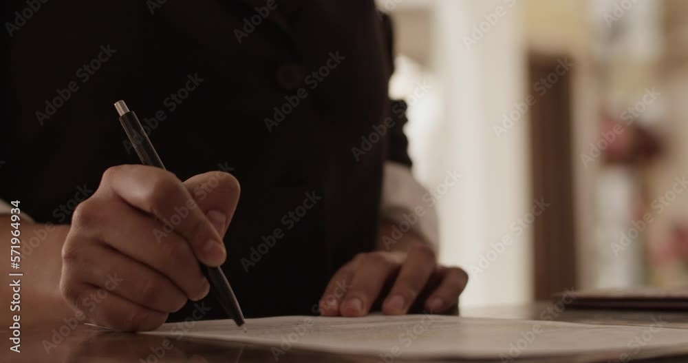Crop anonymous woman signing documents during registration at hotel Crop anonymous woman signing documents during registration at hotel