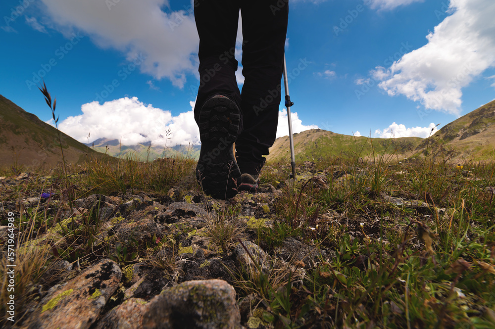 Close-up of boots while hiking on a trail in the mountains. Man walking in sports shoes overlooking nature from the ground Close-up of boots while hiking on a trail in the mountains. Man walking in sports shoes overlooking nature from the ground