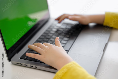 Close-up of child hands typing on the keyboard laptop. Distance learning online education. Schoolboy girl studying at home with digital tablet notebook and doing school homework.