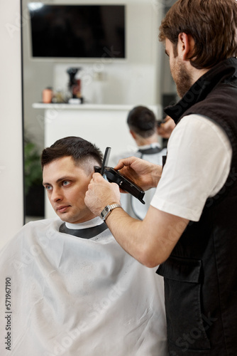 Barber shaving caucasian man in barber shop.