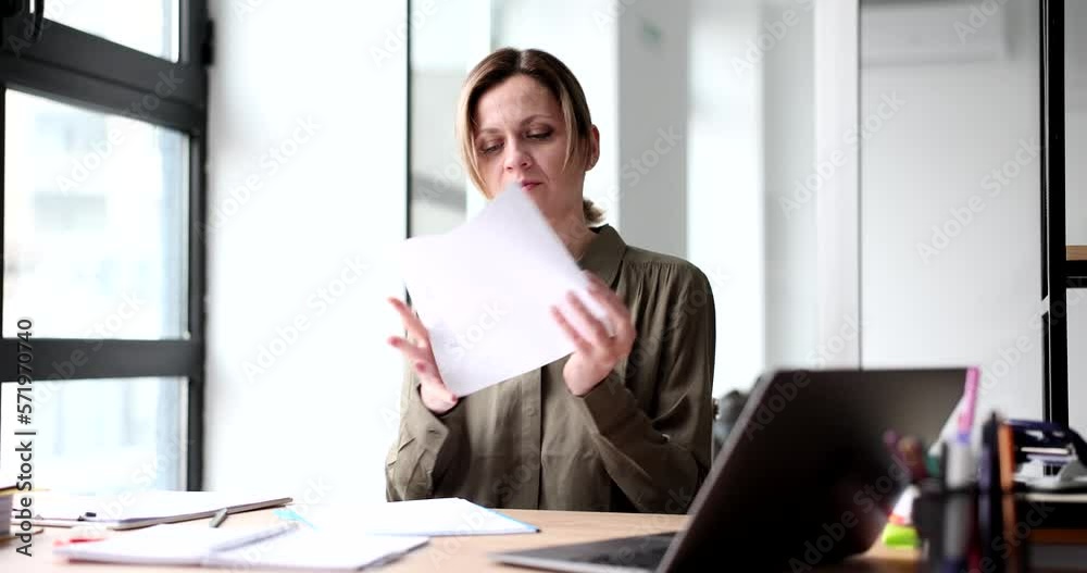 Sad woman writes new ideas and rips paper in office Sad woman writes new ideas and rips paper in office
