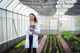 Portrait of Woman agricultural researcher holding tablet while working on research at plantation in industrial greenhouse