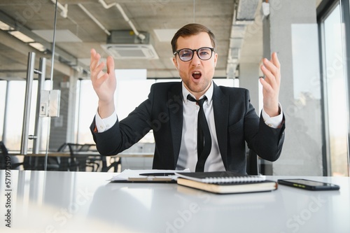 Angry senior businessman sitting at his desk and screaming