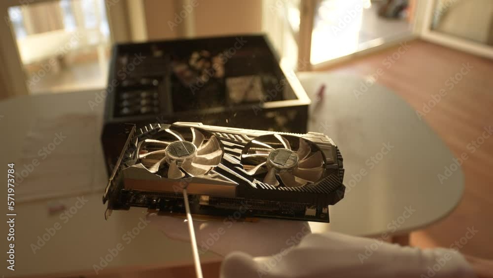 Extreme close-up of unrecognizable professional computer master in gloves cleaning video graphic card using with compressed air spray, slow motion. Concept of desktop PC maintenance and service.