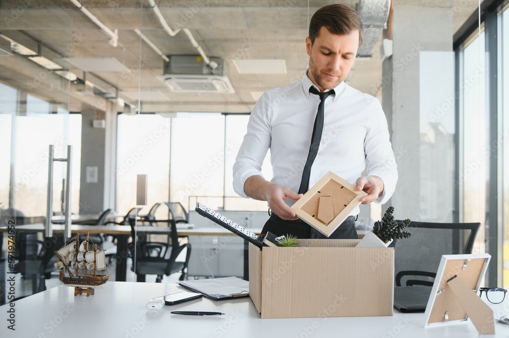 Sad Fired. Let Go Office Worker Packs His Belongings into Cardboard Box and Leaves Office. Workforce Reduction, Downsizing, Reorganization, Restructuring, Outsourcing. Mass Unemployment Market Crisis