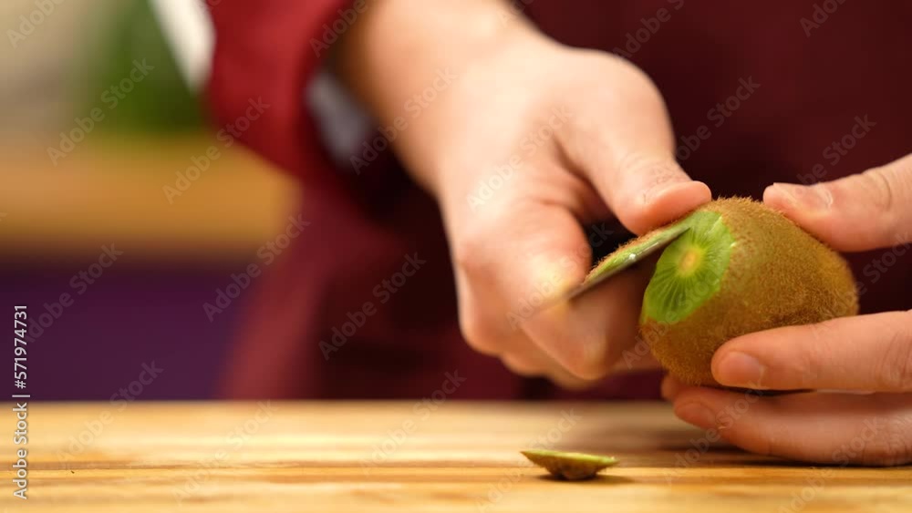Man peeling kiwi, close view. Chef's hand peeling kiwi fruit in kitchen. Healthy Food Concept. High quality 4k video. Preparing fruits for cooking.