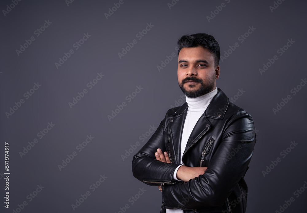 Serious man with dark hair, mustache beard portrait on gray. Guy in leather black jacket looking at camera, arms crossed in front. Horizontal banner, gray background Serious man with dark hair, mustache beard portrait on gray. Guy in leather black jacket looking at camera, arms crossed in front. Horizontal banner, gray background
