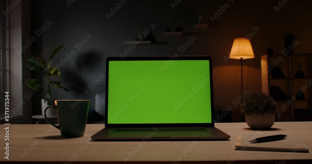 green screen template - a laptop computer on a desk in cozy living room at night. Computer set for distance learning and remote work, technology concept green screen template - a laptop computer on a desk in cozy living room at night. Computer set for distance learning and remote work, technology concept