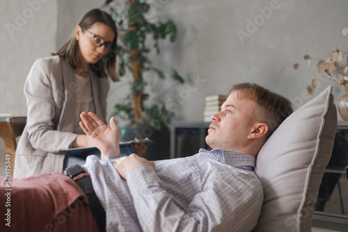 female psychologist conducts psychotherapy session for man. patient in clinic's office on couch talks about his worries and stresses. diagnosis of depression, anxiety disorder. taking care of mental