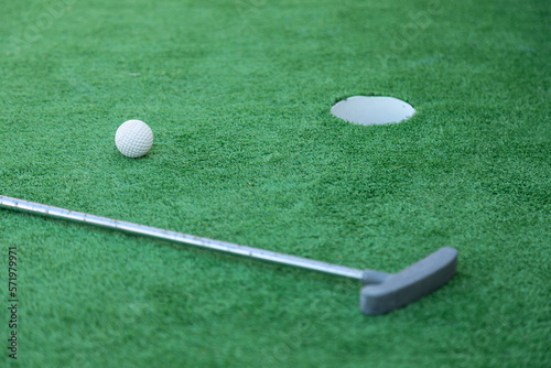 Mini golf equipment, golf club, ball and hole on green ground 