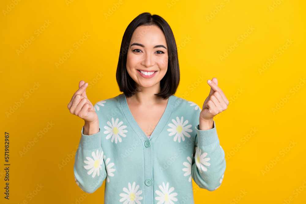 Photo of lovely cute cheerful lady wear trendy daisy flower print clothes arm demonstrate korean heart isolated on yellow color background Photo of lovely cute cheerful lady wear trendy daisy flower print clothes arm demonstrate korean heart isolated on yellow color background