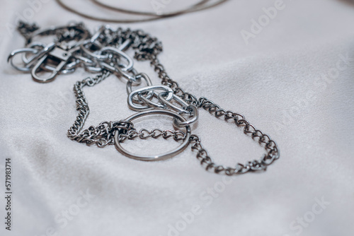 Stylish silver chain jewelry on the neck on a silk shiny background.