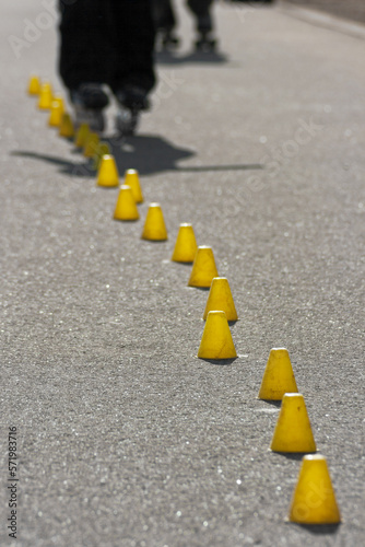 Man slaloming between small yellow cones with his rollerblades