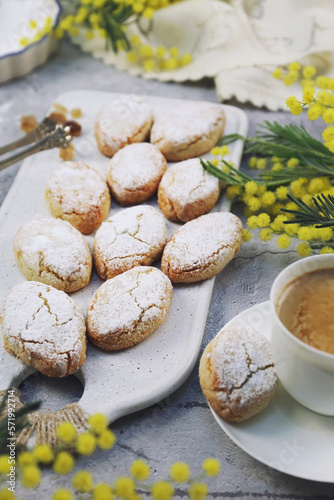 Ricciarelli,  gluten free almond cookies. Italian traditional cookies and cup of coffee. Fresh mimosa bouquet decoration
