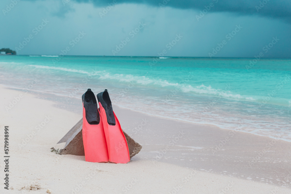 Pink flippers on a white sandy beach against the backdrop of the ocean. Beautiful banner of active recreation. Stylish poster for advertising dive shop and freediving school..
