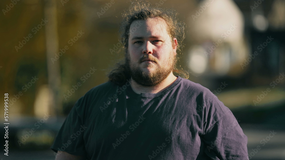 One young casual man standing outdoors looking at camera close up face with serious expression One young casual man standing outdoors looking at camera close up face with serious expression