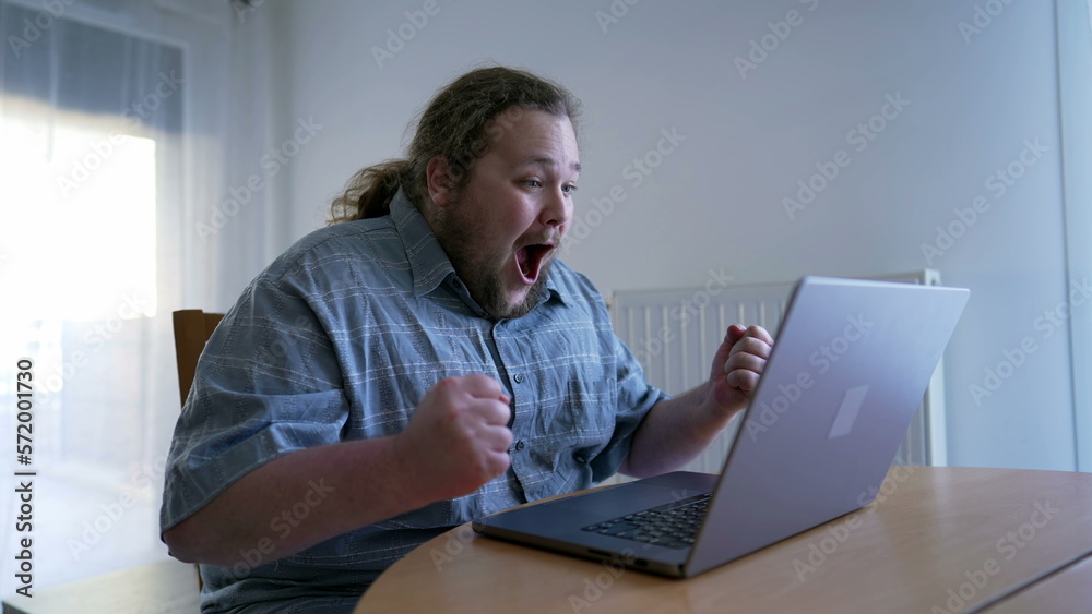 One happy overweight celebrating GREAT news in front of laptop. Over excited person dancing of joy using computer celebrates success One happy overweight celebrating GREAT news in front of laptop. Over excited person dancing of joy using computer celebrates success