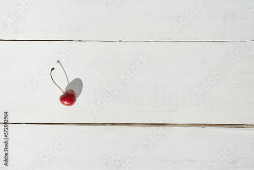 Top view of one cherry berry with a natural shade. Cherry on a white wooden background. With space to copy. High quality photo