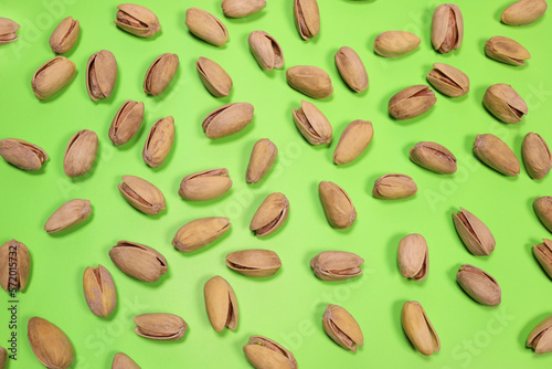 Tasty pistachios texture on green background. flat lay