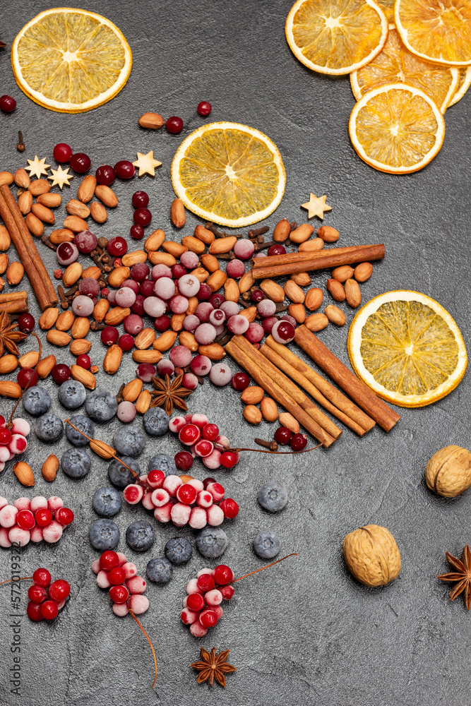 Frozen berries, spices and orange chips on the table. Black background.