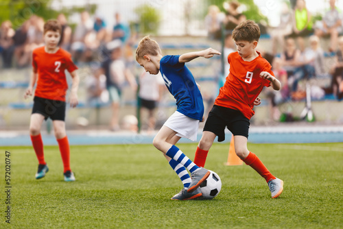 Group of young boys playing soccer game. Football match between youth soccer teams. Junior competition between players running and kicking soccer ball. Kids football tournament final game