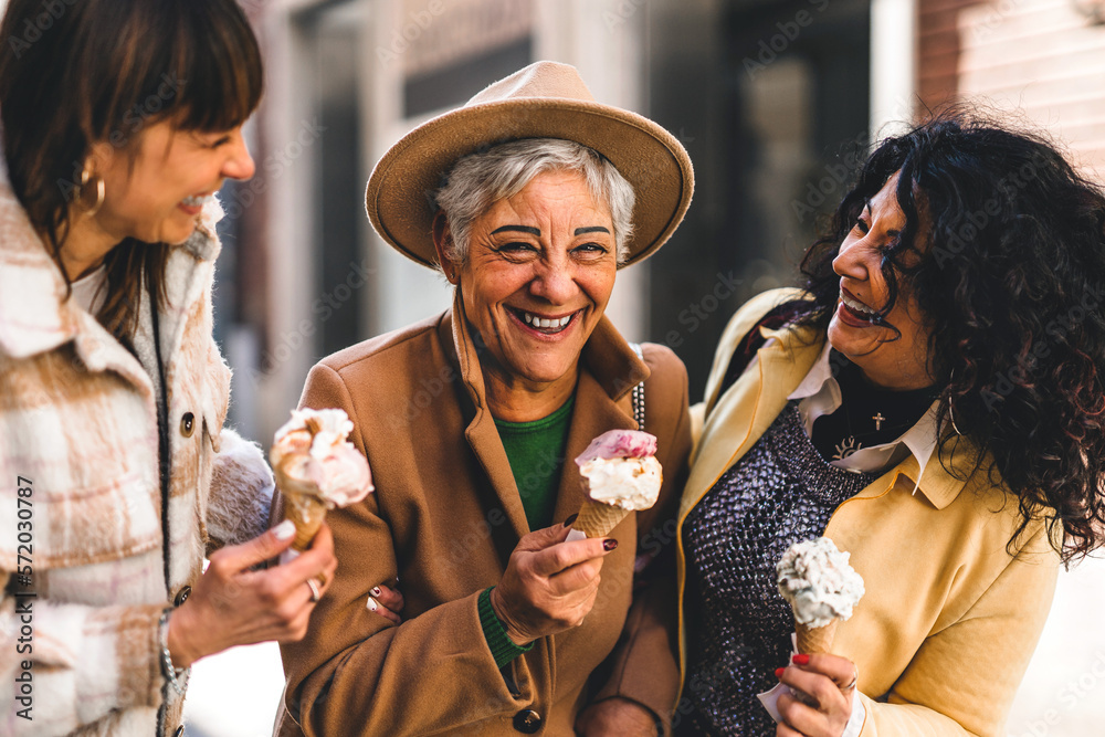 Group of happy women eating ice cream outdoors at city urban street- Three older mature friends girls having fun and walking together outside-Joyful Elderly lifestyle concept - obrazy, fototapety, plakaty 