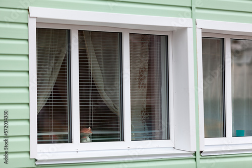 White window openings of plastic windows with an external facade of green siding © Kekyalyaynen