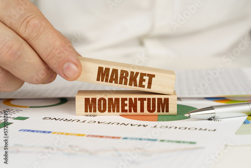 On the table are business charts and diagrams in the hands of a wooden block with the inscription - MARKET MOMENTUM