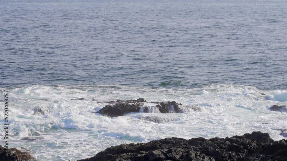 Establishing shot of ocean beach with waves and rocks in slow motion at summer day in Vancouver, Canada, North America. Day time on February 2023. Still camera. ProRes 422 HQ. Establishing shot of ocean beach with waves and rocks in slow motion at summer day in Vancouver, Canada, North America. Day time on February 2023. Still camera. ProRes 422 HQ.