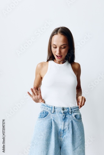 Portrait of a young beautiful woman with tanned skin fashion model on a white background in a white T-shirt and blue jeans with a beautiful smile