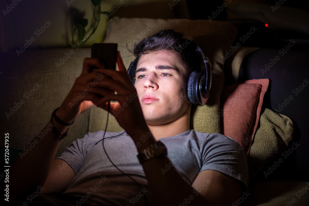 Fototapeta premium Young handsome man watching movie or listening to music