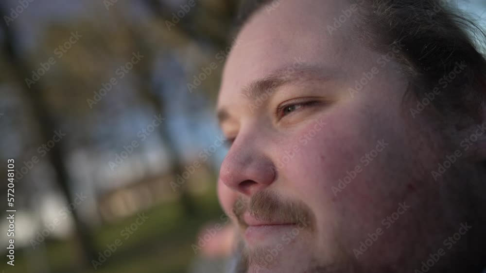 One thoughtful chubby young man relaxed outdoors close up face. Pensive millennial guy smiling in contemplation in nature One thoughtful chubby young man relaxed outdoors close up face. Pensive millennial guy smiling in contemplation in nature