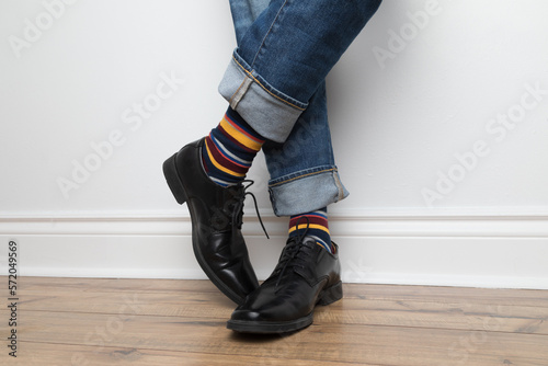 Product photo of men's colourful socks, black dress shoes, and jeans. 