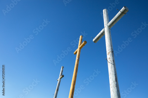 Three wooden crosses nails against bright blue sky © Lenspiration
