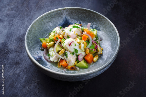 Traditional Peruvian gourmet ceviche sea bass filet piece with sweet potatoes and cancha marinated and served in lime sauce as close-up in a Nordic design bowl photo