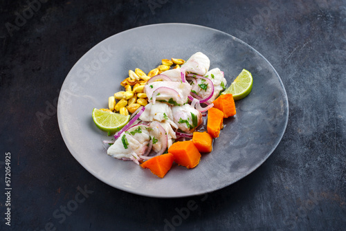 Traditional Peruvian gourmet ceviche sea bass filet piece with sweet potatoes and cancha marinated and served in lime sauce as close-up in a modern design plate