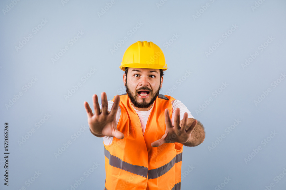 portrait of Hispanic bearded young man engineering and worker with hard helmet in Mexico Latin America on blue background portrait of Hispanic bearded young man engineering and worker with hard helmet in Mexico Latin America on blue background