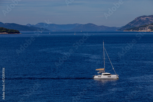 yacht cruises on the Adriatic Sea in the region of Dubrovnik, Croatia, with islands in the background, sunny day, clear weather, intense blue.