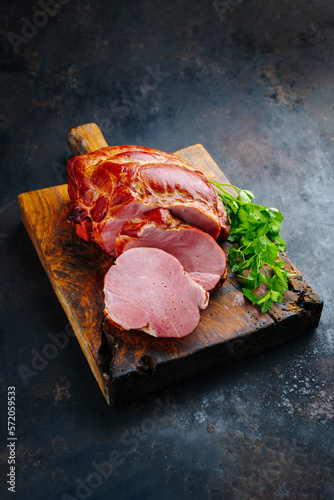 Traditional cured and smoked Baden schäufele of pork shoulder served braised with parsley sliced as close-up on a rustic wooden cutting board