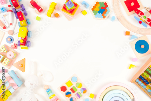Baby kids toys frame background. Wooden educational, musical, sensory, sorting and stacking toys, wooden train, rainbow, colorful building blocks on white background. Top view, flat lay